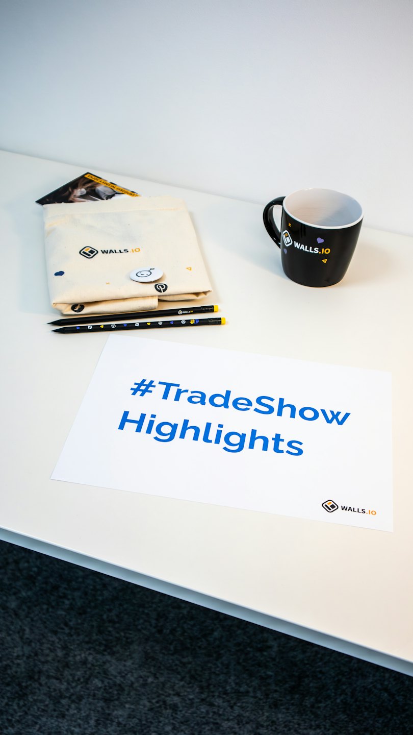 WALLS.IO branded promotional items on a white tabletop.