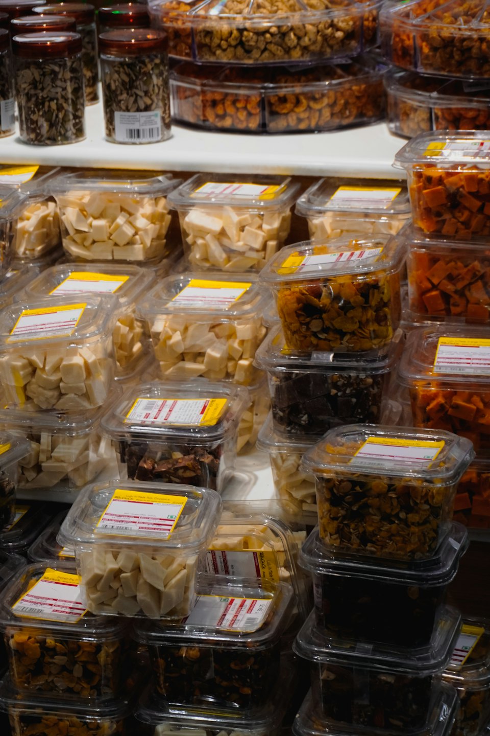 Clear jars and containers of assorted snacks sit on white shelves.