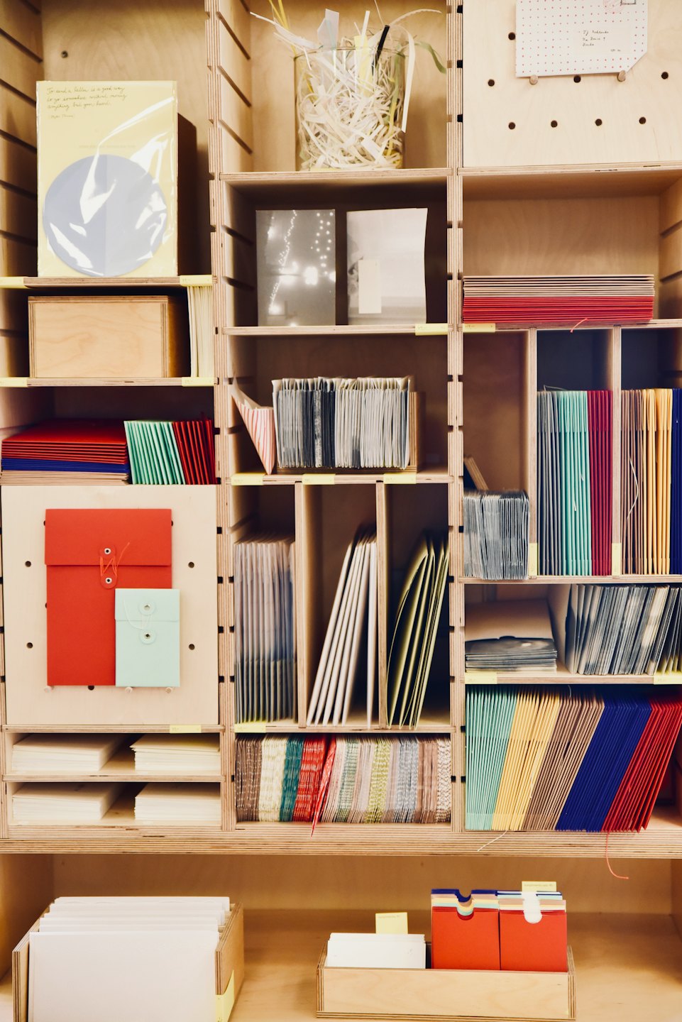 Stationery and paper products neatly displayed on plywood shelving.